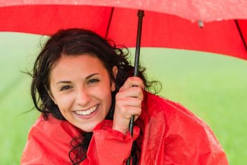 nicht nur durch positives Denken: positiv gestimmte, fröhliche Frau mit Regenschirm
