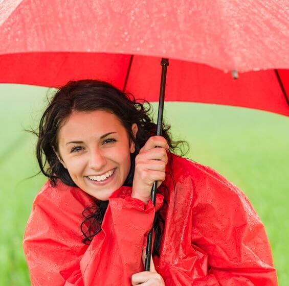 nicht nur durch positives Denken: positiv gestimmte, fröhliche Frau mit Regenschirm