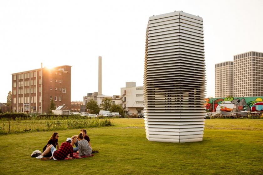 Der Smog Free Tower in einem Park, junge Leute sitzen daneben im Gras