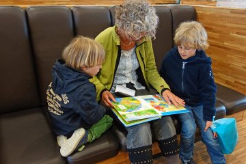 Frau liest zwei Kindern aus Buch vor